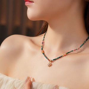 Détail d'un collier pendentif soleil avec perles turquoise et roses sur un mannequin
