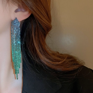 Close-up of dangling rhinestone tassel earrings with blue-green gradient chains