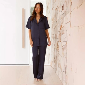 Detail of navy blue satin pajama set with short-sleeved button-up top and long pants