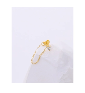 Macro shot of gold floral earrings with zircon chain tassels on textured stone