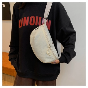 Detalle de un bolso bandolera de nailon blanco llevado sobre una sudadera negra