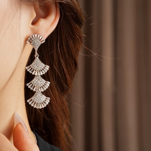 Close-up of silver layered fan earrings with crystals worn by model on neutral background