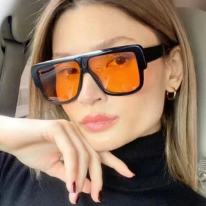 Square oversized sunglasses with black frame and orange lenses worn by a model