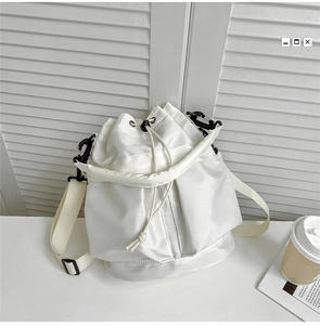 Detailed view of the drawstring closure on a white nylon bucket bag with a minimalist style