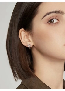 Close-up of a model wearing minimalist silver S925 bow stud earrings with a sleek finish