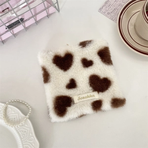 Detail of plush heart pattern coaster with a woven label in a cozy desk setting