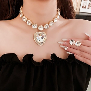Detail of luxury gold necklace set with heart crystal pendant and matching round earrings