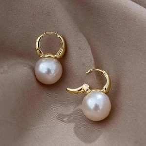 Close-up of pearl drop earrings with gold finish and rhinestone details on silk