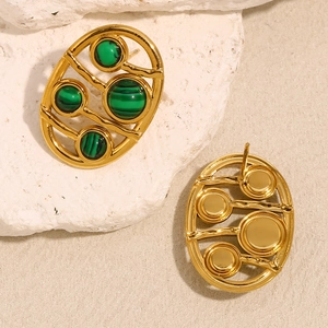 Macro shot of gold-plated hollow oval earrings featuring green malachite stone texture