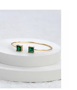Detail of gold-plated open bangle with square emerald-green zircon stone inlay