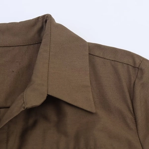 Detail shot of a dark brown poplin shirt dress featuring a lapel collar and twill texture