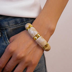 Close-up of geometric acrylic beaded bracelet with golden rings on model's wrist