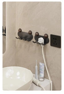 Detail view of black wall hook with wood ball for organizing power plugs and toothbrushes