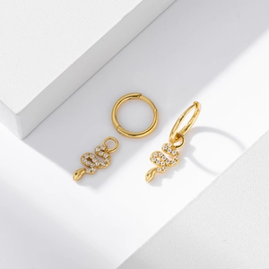 Detailed view of gold snake earrings with pave white zircon on white geometric stones
