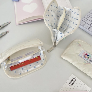 Detailed view of quilted cream wallet with colorful embroidery and star pattern lining