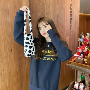 Close-up of fluffy black and white cow print plush cup bag with soft carry handle