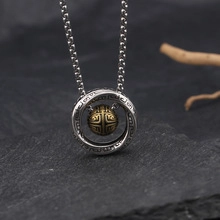 Close-up of vintage silver double-ring necklace with an engraved golden bead pendant
