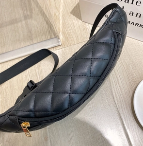 Detailed macro view of black quilted chest bag with golden metal zipper and texture