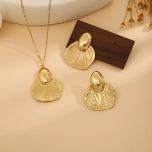 Detailed view of golden leaf textured necklace and earrings set on an elegant tray