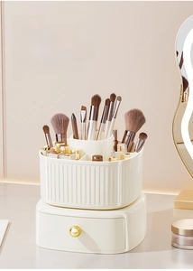 Close-up of a rotating makeup organizer featuring a cream white drawer and gold handle
