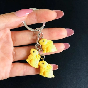 Detailed view of three yellow resin rabbit pendants with textured fur on a metal keychain