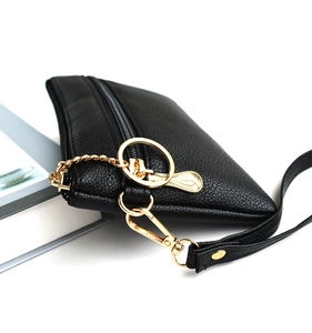 Detail of black lychee grain leather mini bag with gold zipper and round ring keychain