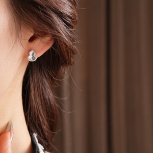 Close-up of gourd-shaped stud earrings with black and white inlay on a female model