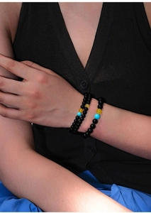 Detail of beaded bracelet set with black round beads and blue agate accents on wrist