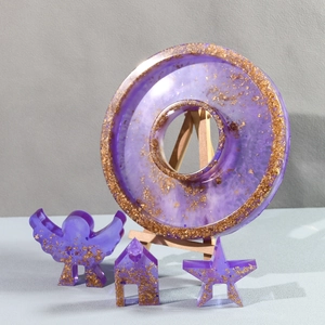 Detail of purple resin angel and house set with gold foil flakes on wood stand