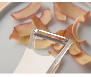 Close-up of white fruit peeler blade and transparent head with vegetable peelings