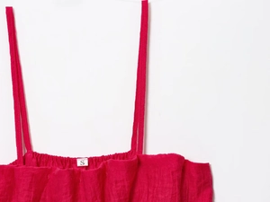Détail du haut rose fuchsia montrant le tissu texturé et l'étiquette de taille S au col
