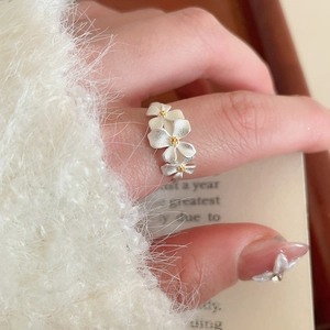 Close-up of three matte flower rings with gold centers on a woman's finger