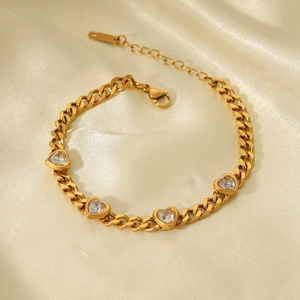 Gros plan d'un bracelet en acier inoxydable doré 18K avec quatre breloques cœur en zircon