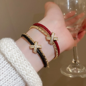 Détail d'un bracelet croisé plaqué or avec zircons micro-pavés et cordon en cuir