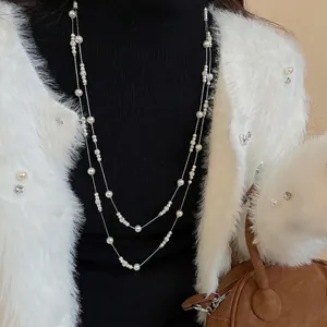 Elegant double-layered pearl necklace with crystal accents worn over a black sweater