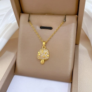 Macro shot of gold mushroom pendant with paved white zircons on a delicate chain