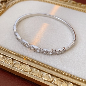 Detail of silver oval link bracelet with zircons displayed in a vintage golden frame