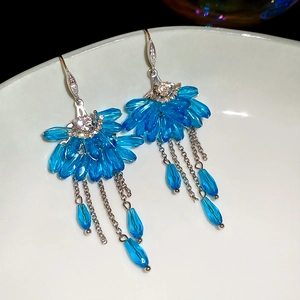 Close-up of blue crystal fan earrings with long tassel chains and zircon accents