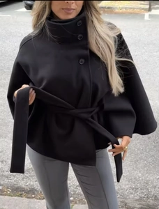 Detailed close-up of a black wool-like cape coat featuring a stand collar and waist belt