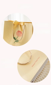 Detail of yellow gift bag with orange floral print, silk bow, and thick cardstock base