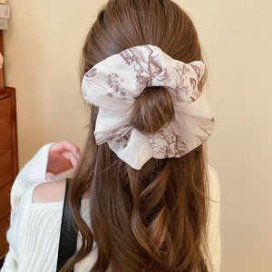 Detail of vintage French toile de jouy print scrunchie styled on a woman's brown wavy hair