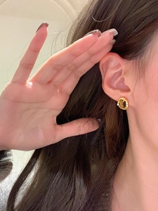 Detail of 18k gold plated tiger eye stone stud earrings with zircons worn on ear