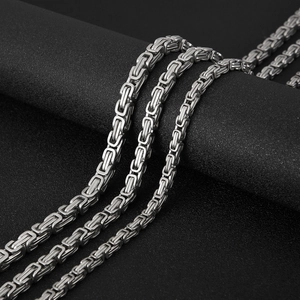 Macro shot of polished silver stainless steel Byzantine chain jewelry on a black texture