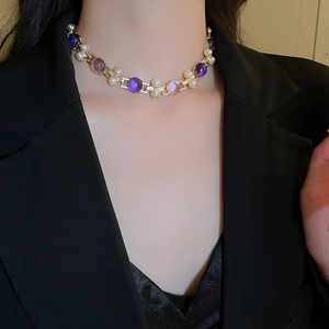 Détail d'un collier vintage doré orné de pierres roses et violettes avec des perles