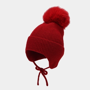 Détail du bonnet rouge à cache-oreilles avec pompon en fausse fourrure et liens