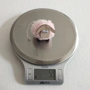 Close-up of handmade pink felt sheep ornament weighing 5.3g on a digital silver scale