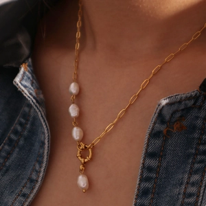 Detail of 18K gold-plated paperclip chain necklace with pearl accents on a denim background