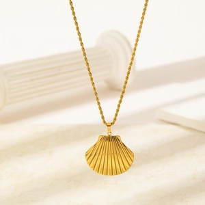 Collier pendentif coquillage doré avec chaîne torsadée sur socle en marbre