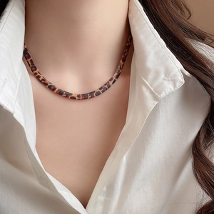 Nahaufnahme der Leopardenmuster-Schlangenkette am Model mit weißem Hemd für Damen