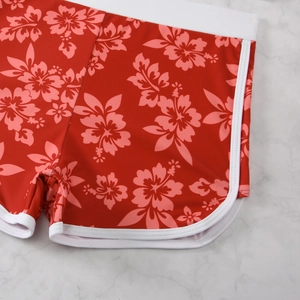 Detail of red floral high-waisted bikini bottoms with white contrast binding and hibiscus print